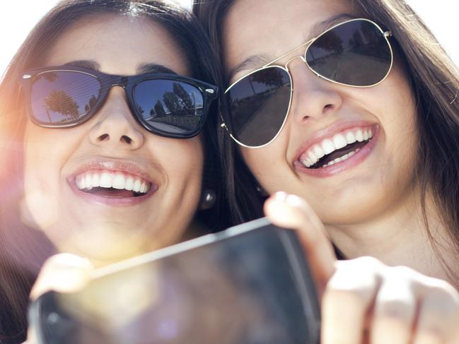 three friends taking photos with a smartphone