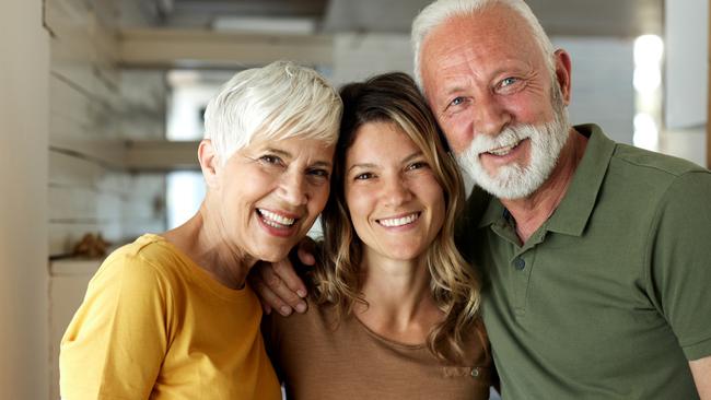 Happy adult daughter enjoying with her mature parents at home and looking at camera; Bank of Mum and Dad generic money