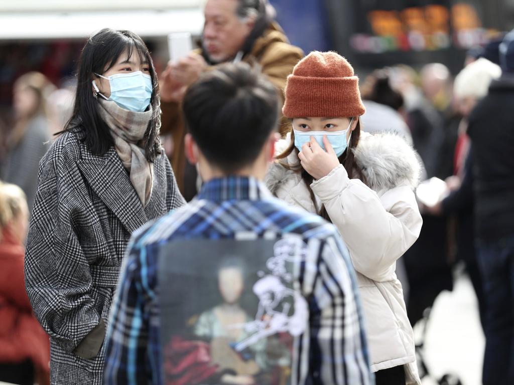 People wearing face masks stand in Piccadilly Circus, London. Picture: PA via AP