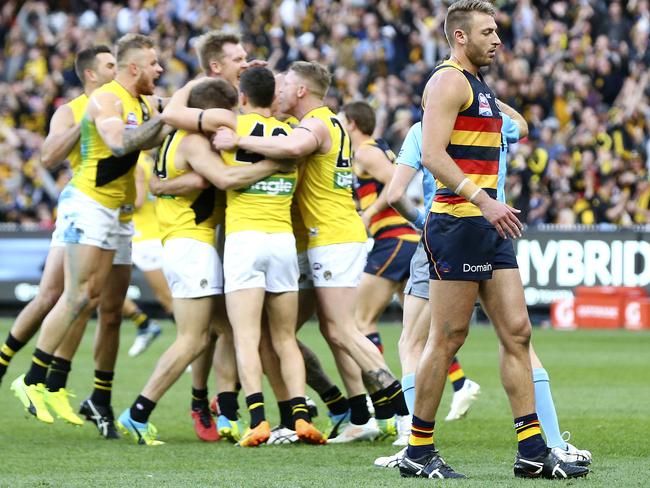 Daniel Talia walks past Tigers players celebrating a goal. Picture: SARAH REED