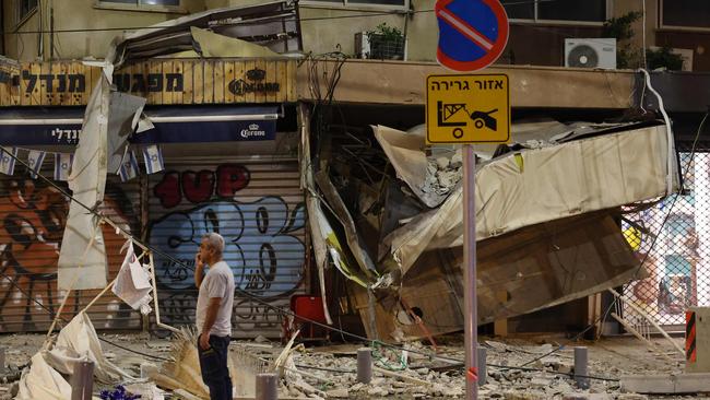 A man stands in front of a damaged shop in Tel Aviv, after it was hit by a rocket fired by Palestinian militants from the Gaza Strip. Picture: AFP