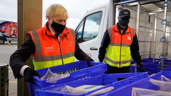 British Prime Minister Boris Johnson loads a delivery van with a tray of shopping during a visit to a distribution centre in London. Picture: AFP