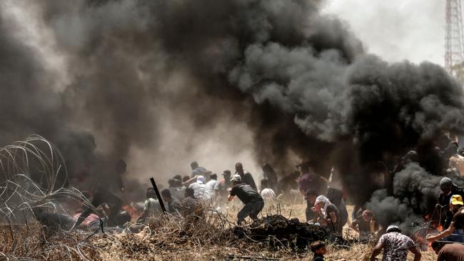 Palestinians clash with with Israeli forces near the border between the Gaza strip and Israel east of Gaza City on May 14, 2018, as Palestinians protest over the inauguration of the US embassy following its controversial move to Jerusalem. Dozens of Palestinians were killed by Israeli fire on May 14 as tens of thousands protested and clashes erupted along the Gaza border against the US transfer of its embassy to Jerusalem, after months of global outcry, Palestinian anger and exuberant praise from Israelis over President Donald Trump's decision tossing aside decades of precedent. / AFP PHOTO / MAHMUD HAMS