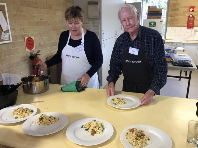 Volunteer instructor Michelle Jansen (left) and John Coye plate up the Moroccan chicken dish during a Men's Kitchen Northern Beaches cooking skills session at the Forestville Community Hal. Picture: Jim O'Rourke