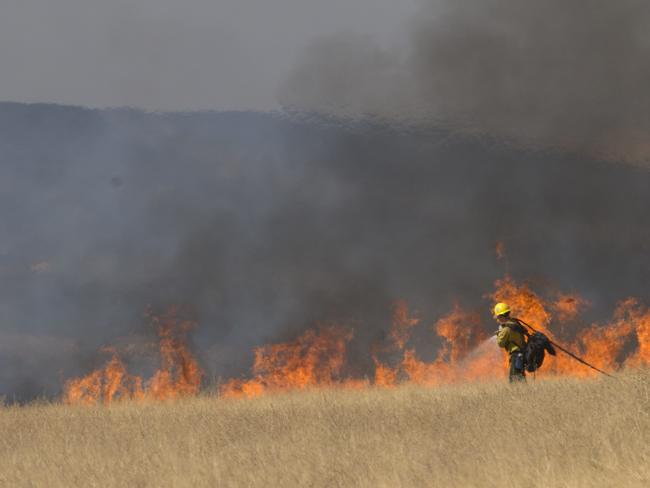 A firefighter puts water on the flames of a fire caused when a US Air Force U-2 spy plane crashed in the Sutter Butte mountains. Picture: AP / Rich Pedroncelli