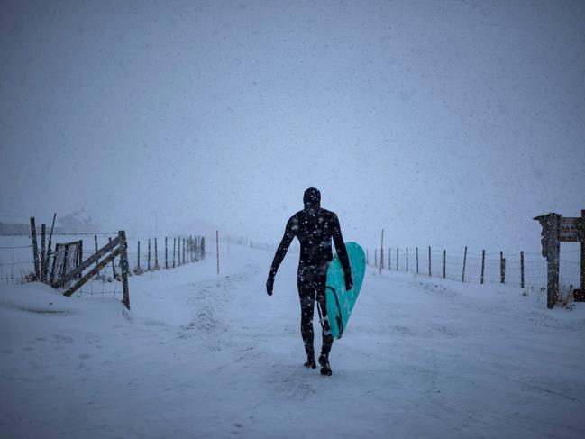 A surfer carries his surfboard as he walks out of the water under snowfall, on March 11, 2018, in Unstad, northern Norway, Lofoten islands, within the Arctic Circle. Picture: AFP