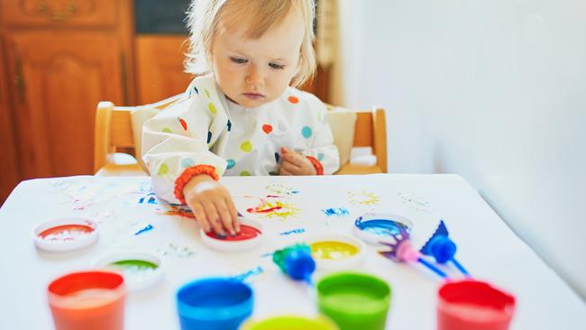 Adorable little girl painting with fingers at home, in kindergaten or preschool. Creative games for kids