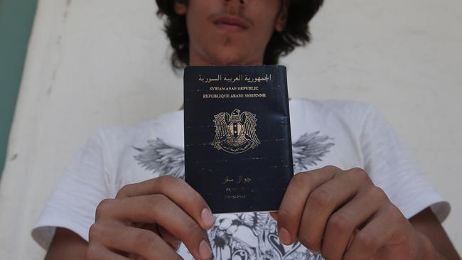 Syrian refugee Mouradin, 16, last name not given, holds his Syrian passport, as he waits to be registered outside the local coast guard building in the Greek island of Leros, Monday, Aug. 17, 2015. This Greek island that was once a place of exile for political prisoners has become one of the country's most welcoming communities for migrants fleeing chaos and war, thanks to a dedicated grass-roots volunteer network and tourists interrupting their vacations to provide what help they can. But even on Leros, a 75-square kilometer (29 sq. mile) rocky outcrop in the Aegean Sea with a permanent population of fewer than 10,000 people, the welcome mat is fraying under the sheer numbers of migrants _ hundreds arrive in smugglers' boats most days _ making the perilous boat journey here across the Aegean Sea from Turkey. (AP Photo/Lefteris Pitarakis)