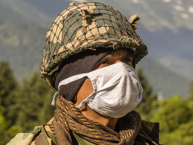 GAGANGIR, KASHMIR, INDIA - JUNE 19: An Indian Border Security Force (BSF) soldier wearing a mask guards a highway as Indian army convoy makes way towards Leh, bordering China, on June 19, 2020 in Gagangir, India. As many as 20 Indian soldiers were killed in a "violent face-off" with Chinese troops on Tuesday in the Galwan Valley along the Himalayas. Chinese and Indian troops attacked each other with batons and rocks. This is the deadliest clash since the 1962 India-China war and both have not exchanged gunfire at the border since 1967. Since the recent clash, there has been no sign of a breakthrough. India said its soldiers were killed by Chinese troops when top commanders had agreed to defuse tensions on the Line of Actual Control, the disputed border between the two nuclear-armed neighbours. China rejected the allegations. It blamed Indian soldiers for provoking the conflict, which took place at the freezing height of 14,000 feet. The killing of soldiers has led to a call for boycott of Chinese goods in India. On Thursday, thousands of people attended the funerals of the 20 slain Indian soldiers. To show their anger, Indians burnt Chinese flags and posters of China's President Xi Jinping in many states. (Photo by Yawar Nazir/Getty Images)