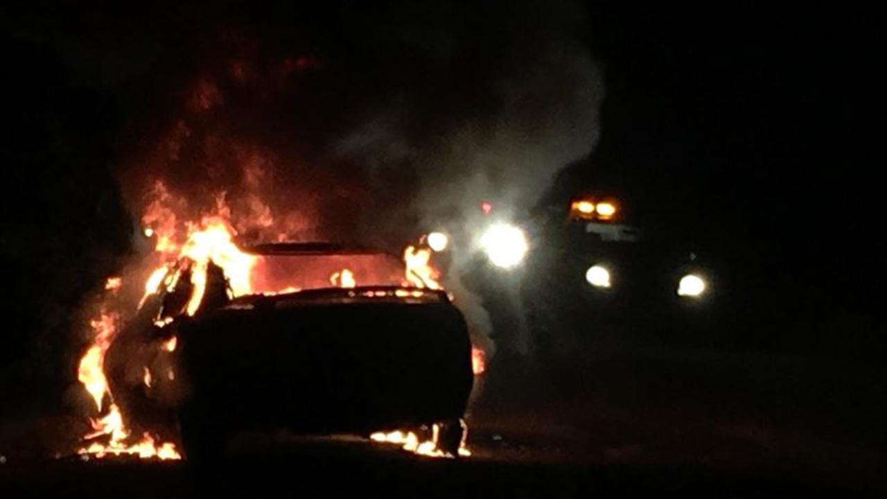 A car that burst into flames at Glenwood on Monday night, was winched onto the road to stop it causing a grass fire.