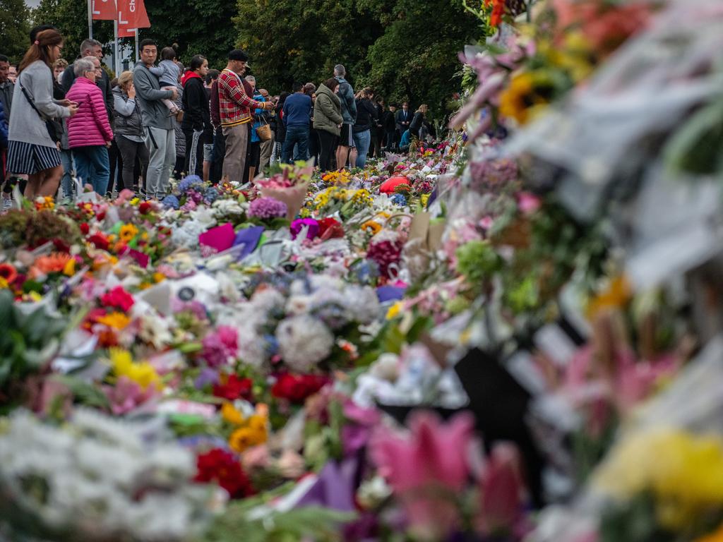 People pause next to flowers and tributes for the victims of the massacre. Picture: Getty