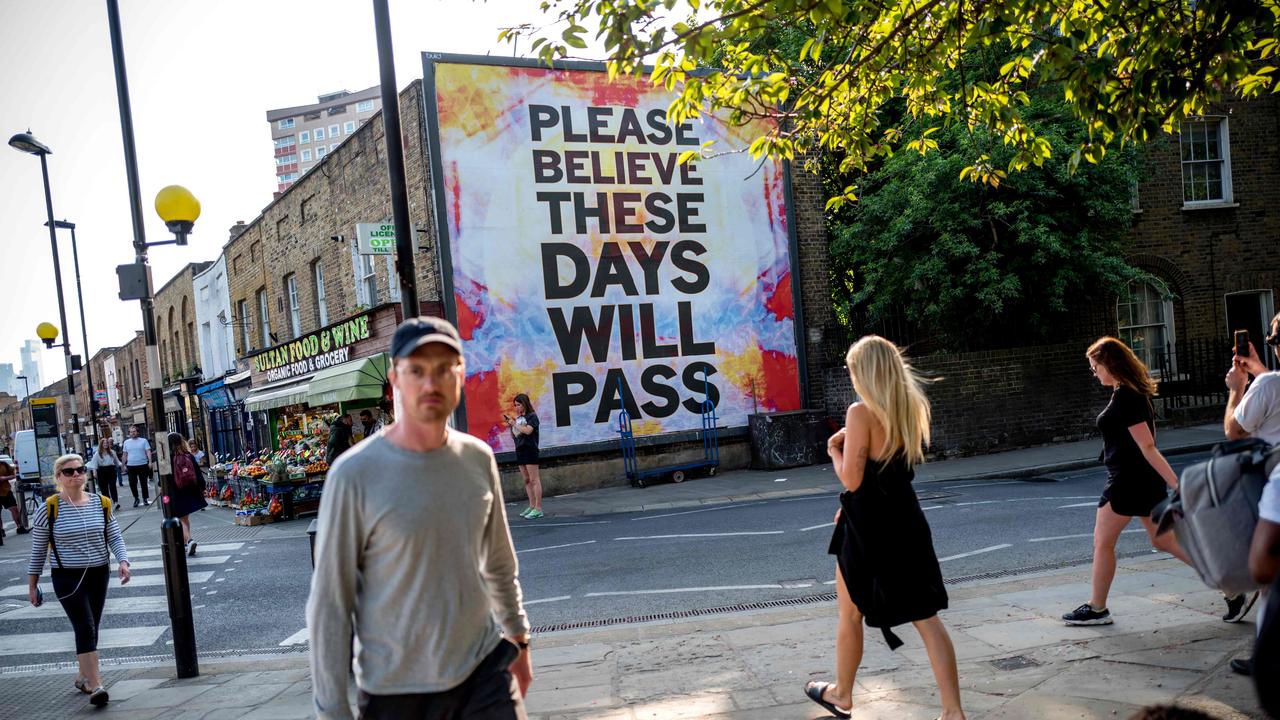 People walk past a billboard reading "Please believe these days will pass" on Broadway Market in East London on April 24, 2020. Picture: Tolga Akmen / AFP