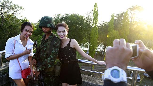 Passers-by with a soldier near a pro-government rally on the outskirts of Bangkok. Picture: AP