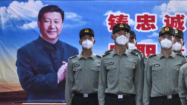 Soldiers of the People's Liberation Army's Honour Guard Battalion wear protective masks as they stand at attention in front of photo of China's president Xi Jinping at their barracks outside the Forbidden City. Picture: Getty Images