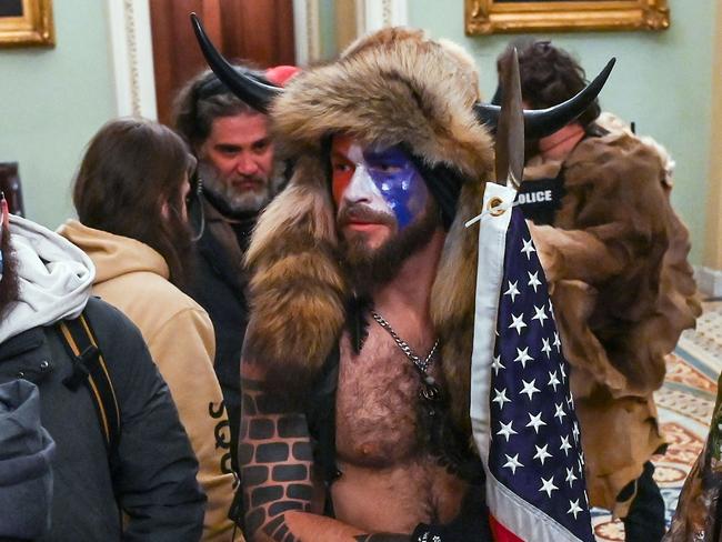 (FILES) In this file photo taken on January 06, 2021, supporters of US President Donald Trump, including Jake Angeli (C), a QAnon supporter, enter the Capitol in Washington, DC. - Authorities announced new arrests and charges on January 9, 2021, over the violent incursion into the US Capitol, including Jacob Anthony Chansley, also known as Jake Angeli, and two others -- one of them a newly elected state official -- were charged in federal court in connection with the violence, according to the US attorney's office for the District of Columbia. (Photo by Saul LOEB / AFP)