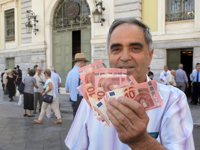 Taking what they can ... Pensioner Giorgos Petropoulos shows ten euros notes which he received from the National Bank of Greece in Athens. Picture: AP/Spyros Tsakiris