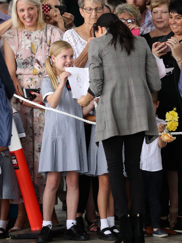 An adoring fan hands Meghan a poster.