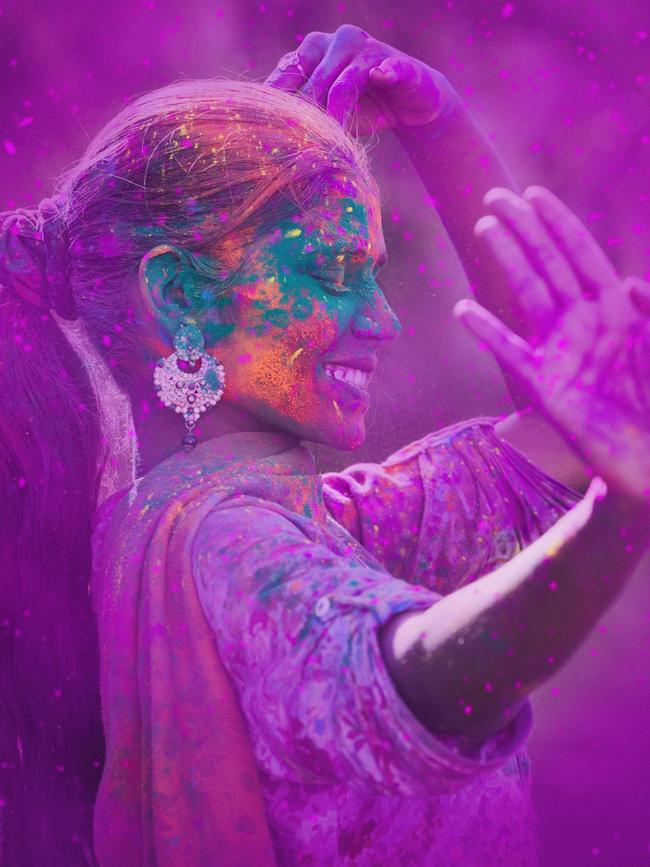 Young woman covered in colored dye celebrating Holi festival in Jaipur, India.