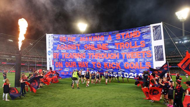 Melbourne players send a powerful message to online trolls as they tear through their banner. Picture: Getty Images