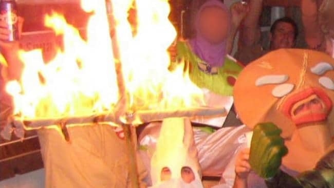 A soldier wearing a Ku Klux Klan costume holds a burning cross at a party attended by Ben Roberts-Smith in footage aired on 60 Minutes.