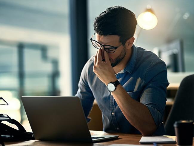 Shot of a young businessman experiencing stress during a late night at work