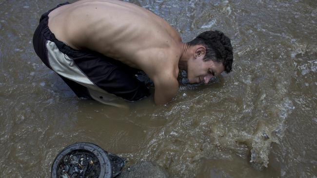 David Garcia keeps his head just barely above water as he scrapes the bottom of the polluted Guaire River in search of gold and anything of value to sell in Caracas to put food on the table. Picture: AP/Ariana Cubillos