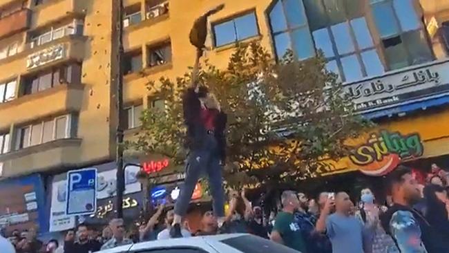 A young woman waves a hijab as she stands atop a car during a protest in Mashhad, in northeastern Iran, on September 20. Picture: AFP