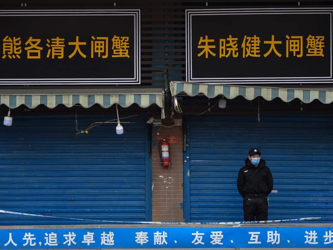 A security guard stands outside the Huanan Seafood Wholesale Market where the coronavirus was detected in Wuhan on January 24, 2020 - The death toll in China's viral outbreak has risen to 25, with the number of confirmed cases also leaping to 830, the national health commission said. (Photo by Hector RETAMAL / AFP)