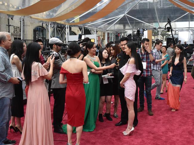 Journalists interview Chinese actress Huang Shengyi (C) at the red carpet outside the Dolby Theatre as preparations are underway for the 87th annual Academy Awards in Hollywood, California on February 21, 2015. The 87th Oscars take place on February 22 at Hollywood's Dolby Theatre. AFP PHOTO/MLADEN ANTONOV