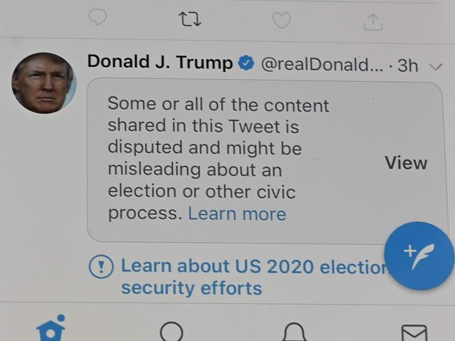 (FILES) In this file photo taken on November 05, 2020 shows a mobile phone placed on a US flag with Tweets from US President Donald Trump masked with warnings imposed by Twitter stating that they may be incorrect. - Twitter labeled 300,000 tweets related to the US presidential election as "potentially misleading" in the two weeks surrounding the vote, making up 0.2 percent of election-related posts, the company said November 12, 2020. (Photo by Robyn Beck / AFP)