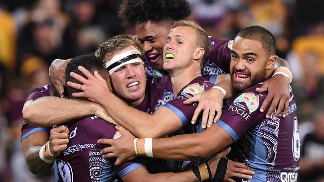 Manly players celebrate a try against the Broncos.