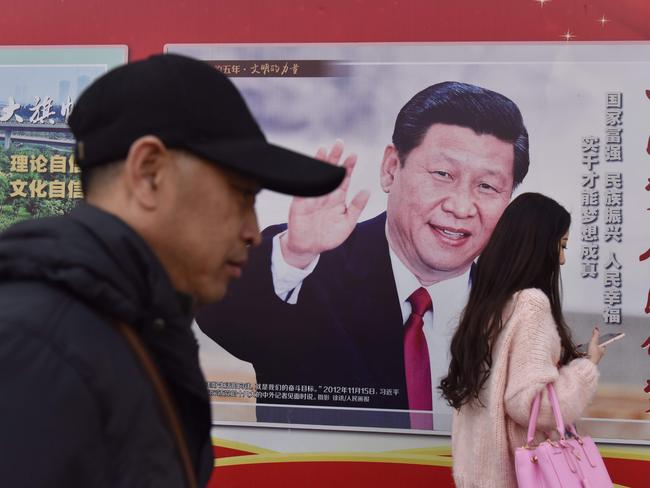 People walk past a poster of Chinese President Xi Jinping beside a street in Beijing. Xi Jinping's tightening grip on China had already earned the leader comparisons to Mao Zedong, but they came into even sharper focus after the party paved the way for him to assume the presidency indefinitely. Picture: AFP/Greg Baker