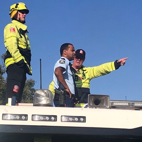 A senior firefighter points out the location of the multiple fires to police, while standing on top on a fire truck. Picture: Jim O’Rourke