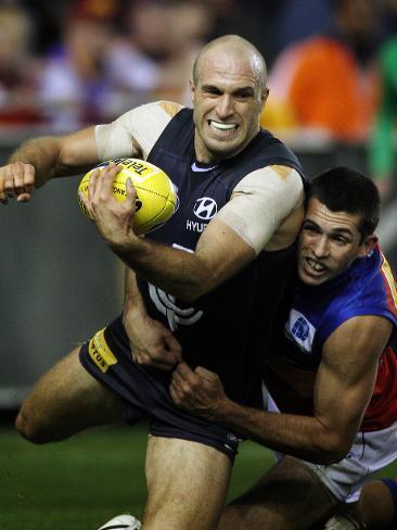 Chris Judd looks to handball clear as he is tackled by Tom Collier of Brisbane.