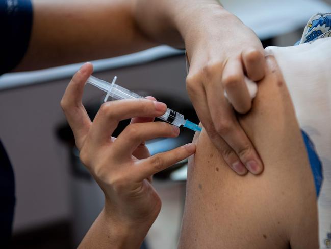 A healthcare worker gives a dose of the Coronavac vaccine to a woman at a vaccination center in the Bicentenario Park, in Santiago, on February 10, 2021. - Chile surpassed one million people vaccinated against COVID-19 on February 9, 2021, six days after starting the mass immunization process in older adults, who joined the medical staff that has already been inoculated since December, the Ministry of Health reported. (Photo by Martin BERNETTI / AFP)