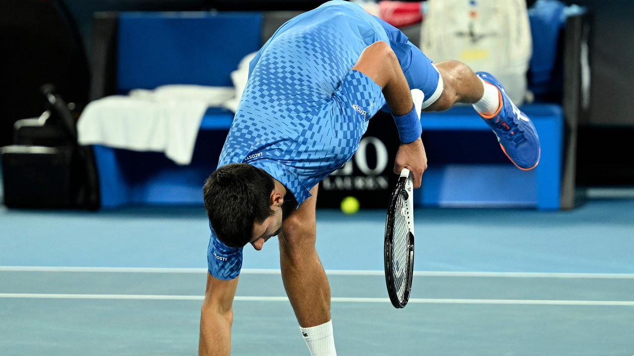 Serbia's Novak Djokovic touches the court as he celebrates victory against Australia's Alex de Minaur during their men's singles match on day eight of the Australian Open tennis tournament in Melbourne on January 23, 2023. (Photo by MANAN VATSYAYANA / AFP)