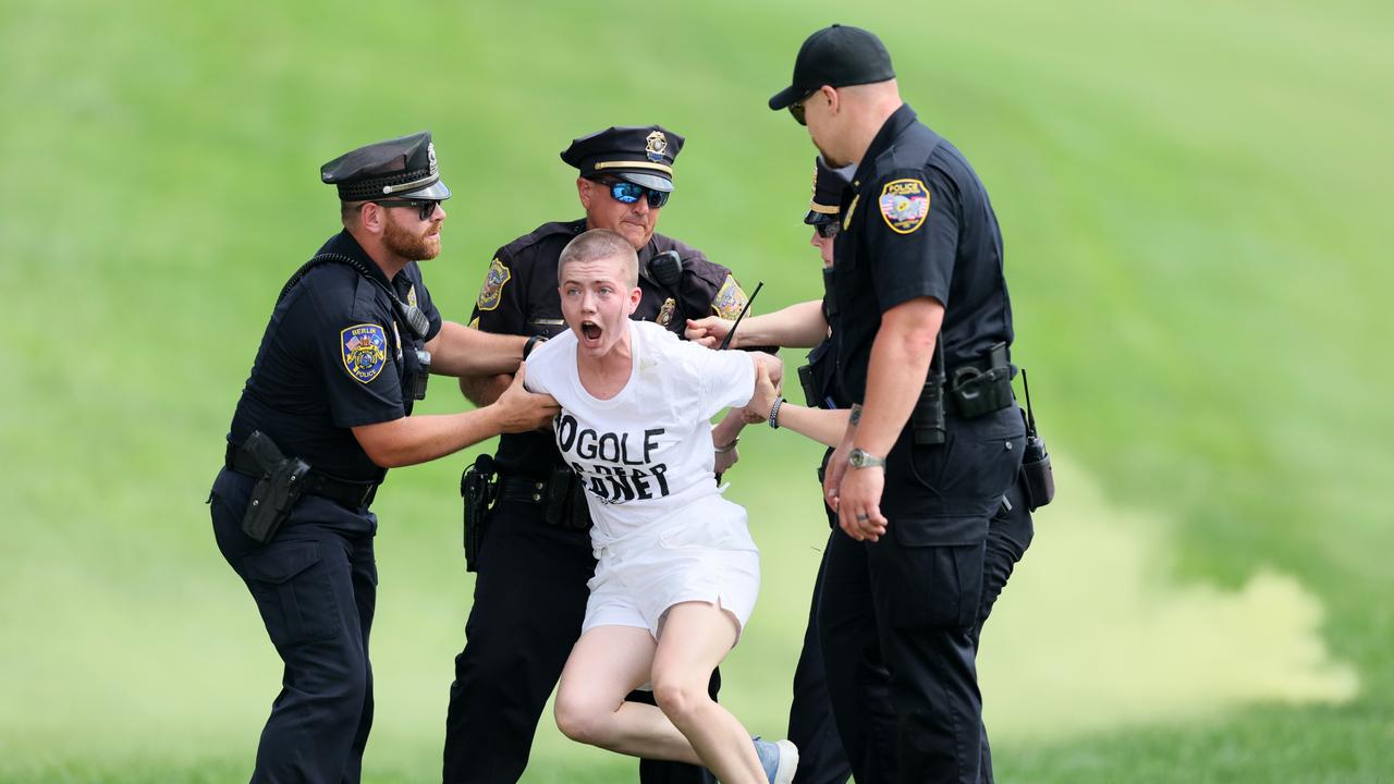 Climate change protestors are ushered off the 18th green by police officers during the final round of the Travelers Championship at TPC River Highlands. (Photo by Andy Lyons/Getty Images)