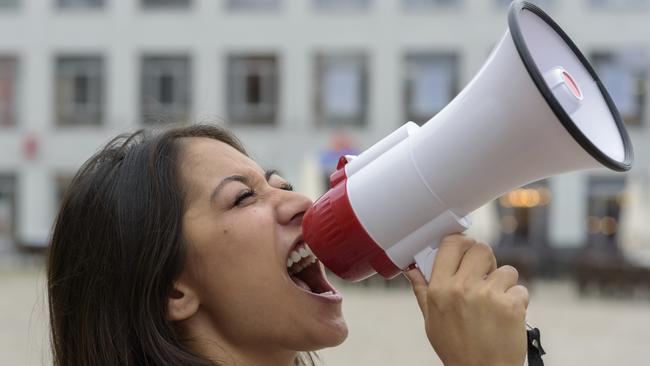 Woman yelling into a bullhorn on an urban street voicing her displeasure during a protest or demonstration, close up side view of her face. Picture: iStock to go with question: Should I include my involvement with political and activist groups on my resume?