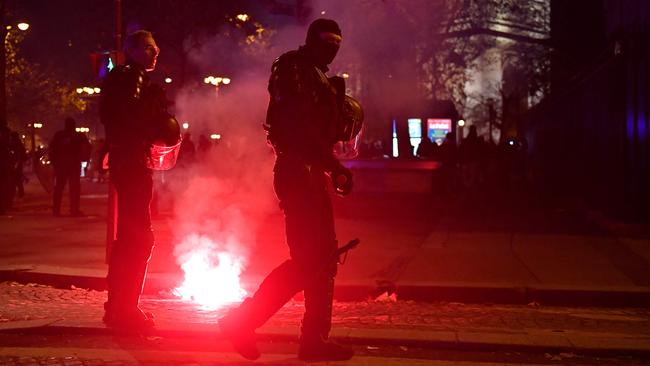 Police officers walk past a smoke flare after France's victory over Morocco