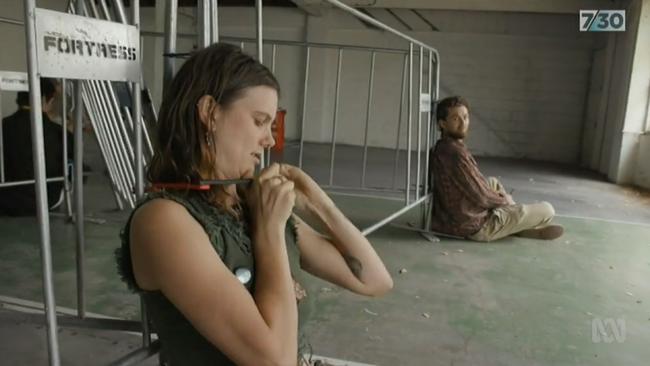 A girl with a bike lock chains herself by her neck to the barricade. Picture: ABC 7.30