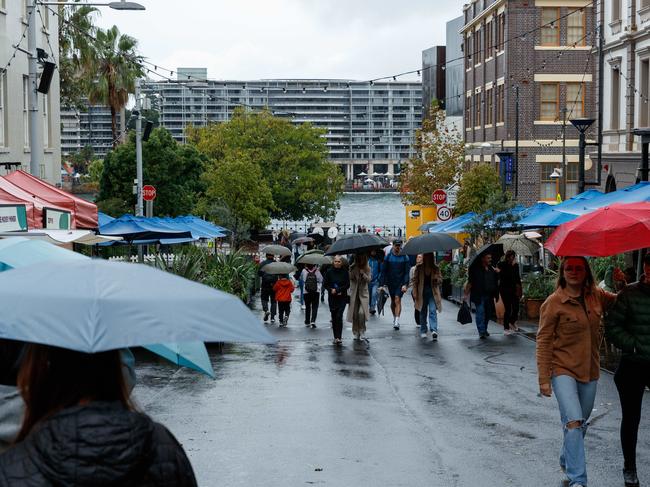 SYDNEY, AUSTRALIA - NewsWire Photos MAY 11 2024. People brave the weather to sightsee around The Rocks. Wild weather will continue to batter NSW, with unrelenting rain that has lingered over Sydney forecast to stick around, and severe thunderstorms predicted over the weekend. Picture: NCA NewsWire / Max Mason-Hubers