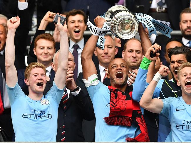 Manchester City's Belgian captain Vincent Kompany (C) lifts the winner's trophy as the players celebrate victory after the English FA Cup final football match between Manchester City and Watford at Wembley Stadium in London, on May 18, 2019. - Manchester City beat Watford 6-0 at Wembley to claim the FA Cup. (Photo by Daniel LEAL-OLIVAS / AFP) / NOT FOR MARKETING OR ADVERTISING USE / RESTRICTED TO EDITORIAL USE