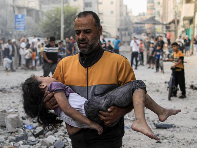 A Palestinian man carries an injured a girl following an Israeli strike, in Khan Yunis in the southern Gaza Strip on October 14, 2023. Picture: AFP.