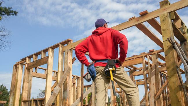 Developing Queensland - roofer, carpenter working on roof structure at construction site.