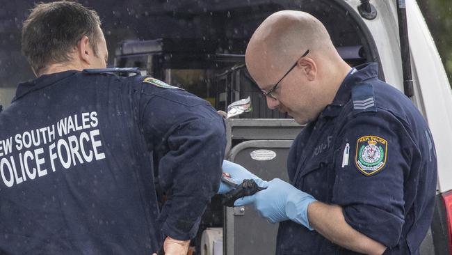 Police inspect a burnt firearm in Berala, western Sydney, where a car was torched after the shooting of senior bikie Tarek Zahed and his brother. Picture: Liam Mendes / The Australian