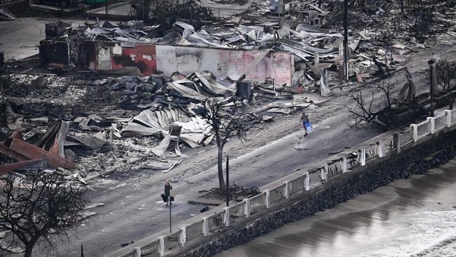 People walking past destroyed buildings on Front St, Lahaina in the aftermath of wildfires in western Maui, Hawaii. Picture: AFP