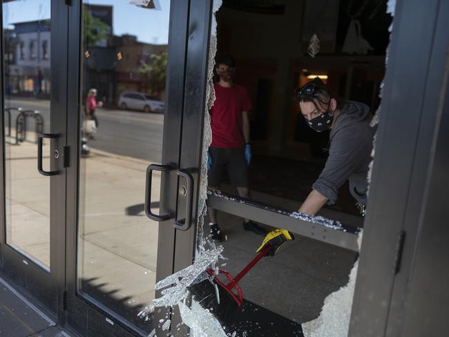 An employee cleans up broken glass from a window of a theatre hit by gunfire. Picture: AP