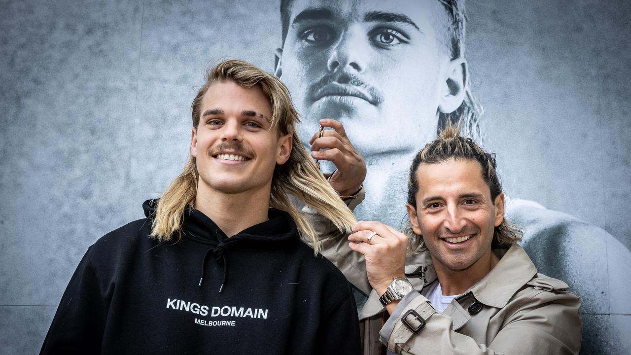 Western Bulldogs star Bailey Smith has his mullet trimmed by hairdresser Joey Scandizzo at King's Domain. Picture: Jake Nowakowski