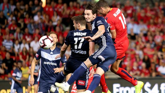 Adelaide’s George Blackwood climbs between two defenders to score for the Reds against Melbourne Victory at Coopers Stadium. Picture: AAP