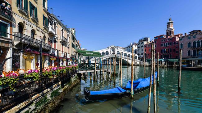 A view shows clear waters by a gondola outside Hotel Marconi (L) in Venice's Grand Canal near the Rialto Bridge (Rear) on March 18, 2020 as a result of the stoppage of motorboat traffic, following the country's lockdown within the new coronavirus crisis. (Photo by ANDREA PATTARO / AFP)